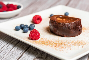 Chocolate coulant, with raspberries and blueberries decoration on a gray decoration background