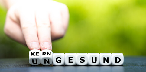 Hand dreht Würfel und ändert das Wort ungesund in kerngesund.