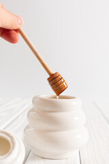White Jar with honey on a white background. Honey spoon in jar. Jar with honey. Honey spoon