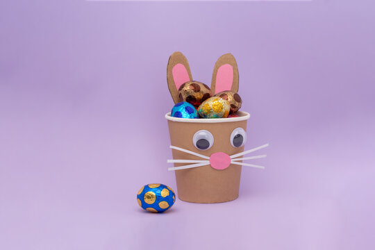 bunny craft from a paper cup filled with chocolate eggs in foil, holiday activity for kids