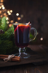 Christmas drink. Sangria or mulled wine on wooden background with christmas lights and fir branches