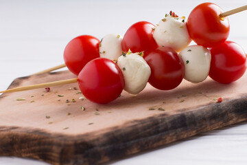 Italian caprese salad with mozzarella balls and tomatoes, on wooden background