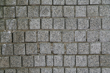 Street paving stones top view with selective focus. Abstract background of old cobblestone pavement, road surface. Textured pavement of lined granite gray stones of different size and square shape.