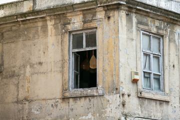 Old crumbling house exterior facade with two windows. Photo closeup of pure aged dirty building outside on cityscape background, horizontal picture, view at corner of the slum's building