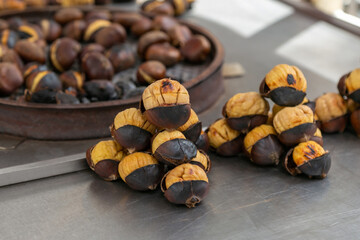 Selective focus on chestnuts. Delicious roasted brown chestnuts for sale on the street. Fresh organic traditional street food. Fried chestnuts ready to eat freshly prepared, background close-up