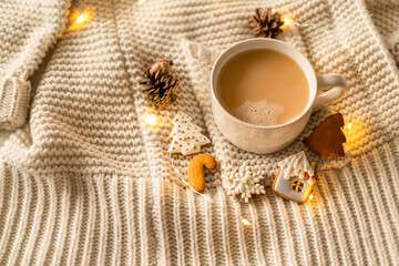 Christmas decor. Mug and Christmas cookies on a knitted sweater. Cozy rest