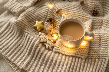 Christmas decor. Mug and Christmas cookies on a knitted sweater. Cozy rest