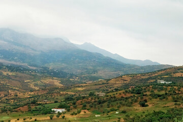 Moroccan landscape with foggy mountains and fields.