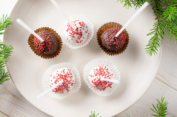 Cake pops on the plate and Christmas fir branches. Top view. Delicious dessert.