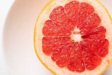 Fresh tasty grapefruit on plate. Half of grapefruit on white background