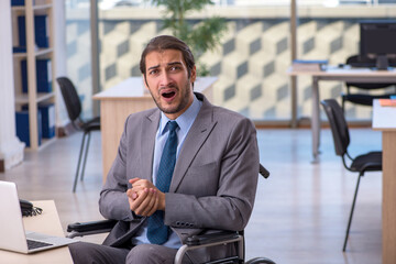 Young male employee in wheel-chair working in the office