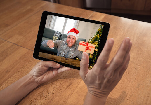 Screen tablet image of man celebrating virtual christmas online on video call due to COVID-19
