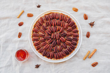 Delicious freshly baked homemade pecan pie on white tablecloth. Sweet food from above. Popular...