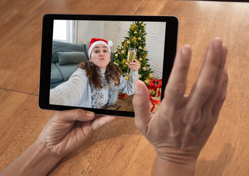 Screen tablet image of woman celebrating virtual christmas online on video call due to COVID-19