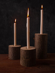 Zero waste concept, natural wooden stump candle holders on brown table. Burning candles on dark background. Spa wellness relaxation, eco-friendly handcrafted home design.No plastic interior decoration