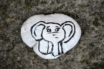 Ein Elefant - Kinderzeichnung auf einem weißen herzförmigen Stein - Das Bemalen von Steinen ist...