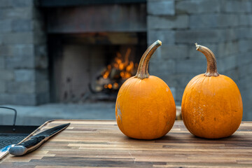 Two sugar pumpkins on a cutting board about to be sliced and roasted.   Cooking outside to make this pumpkin puree. - 395013303