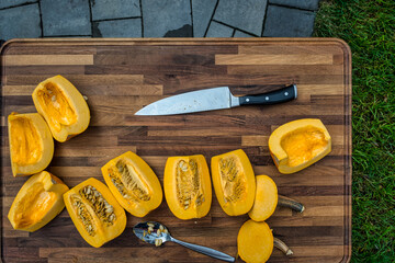 Slicing two sugar pumpkins on a cutting board about to be roasted.   Cooking outside to make this pumpkin puree.