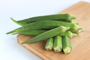 Fresh vegetable okra on wooden tray on white background       