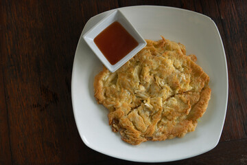 Crab Meat Omelette Served with dipping sauce and chili sauce Put on a white plate.