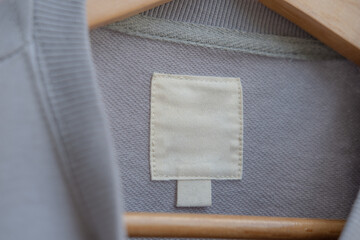 Clothing label on light gray fabric.  Fashion brand name mock up, closeup, top view - 395016506