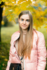 Attractive young woman enjoying her time outside in park with sunset in background. Beautiful young blond woman enjoying. Autumn Portrait of beautiful young woman.