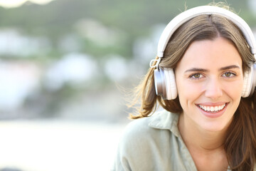 Happy woman wearing headphones looks at camera