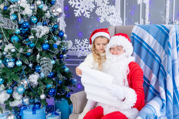 Fototapeta na wymiar Santa Claus reads a letter from a child at the Christmas tree, new year and Christmas concept