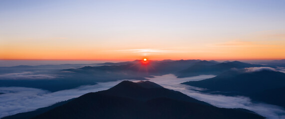 Naklejka na ściany i meble Beautiful panoramic landscape of foggy mountains at sunrise.