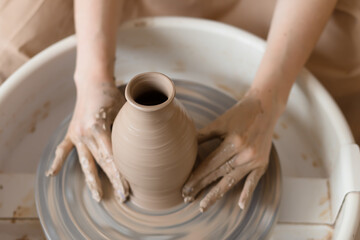 Fototapeta na wymiar close up hands of potter at work. woman make vase from clay on pottery wheel. hobby concept.