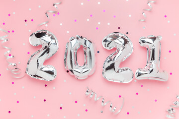 Foil balloons in form of numbers 2021. Silver color air balloons on pink background. Flat lay