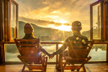 Happy young couple watching lake view at coffee shop in the morning sunrise, Ban Rak Thai village,...