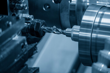 The multi-tasking CNC lathe machine drilling the metal shaft parts. Hi-precision manufacturing  process by CNC turning machine.