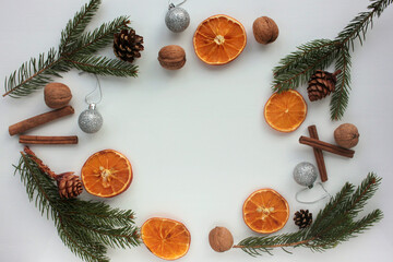 Fototapeta na wymiar Christmas background with christmas decorations. Flat lay winter holiday composition with fir branches, walnuts, dried oranges, cones, and cinnamon sticks. Top view, copy space