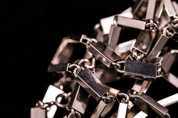 A metal/silver necklace on a dark background.