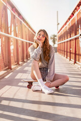 Skater girl sitting on a skateboard. Portraits of a young woman with a longboard