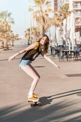 Skater girl riding a long board skate. Cool female urban sports. California style outfit. Woman on skateboard wearing pink glasses