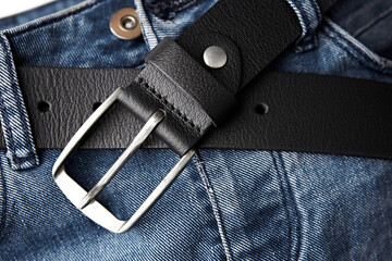Black leather belt on denim. Jeans belt. Fastened fashionable men's leather belt with dark matted...