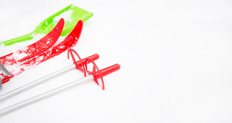 Children's red skis with sticks and a green snow shovel-layout in the snow. Winter outdoor activities, family fun. White natural frosty background. Copy space