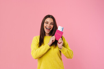 Happy brunette girl smiling while posing with passport and tickets