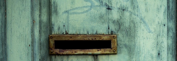 old mailbox slot on wooden turquoise door, close up shot.
