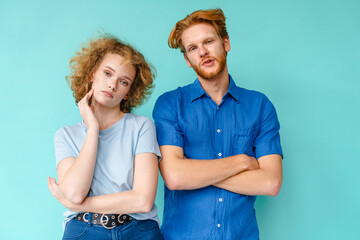 Bored young couple standing isolated over blue