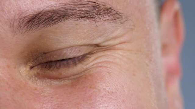 Man look brown eye, pupil with iris. Male smile, positive emotion. Natural skin. Wrinkle around eye is fold, ridge or crease on skin. Cosmetology and skincare