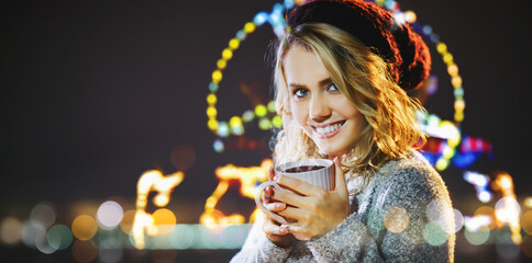 Pretty woman drinks mulled wine at the Christmas market at night