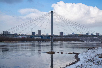 Cable-stayed bridge over the river against the background of the cityscape in winter.