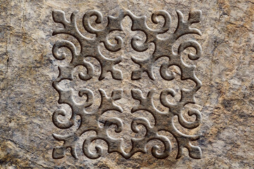 Ornamental print on the stone surface. Vintage ornament on the stone. Close-up seamless texture. Stone texture. Pattern on the stone. Embossed pattern. Wallpaper.