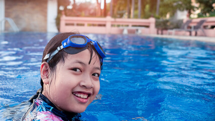 Pretty little girl in swimming pool with smile and happy in summertime