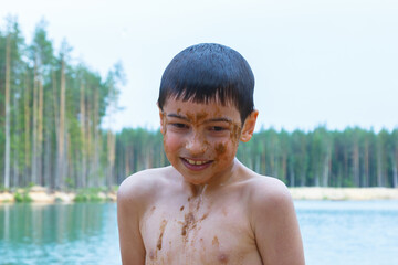boy smeared in the sand on the background of the lake, outdoor recreation