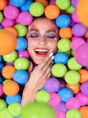 Fototapeta na wymiar A woman smiling, with her eyes closed, immersed in colored balls. Joy concept.Selective focus.