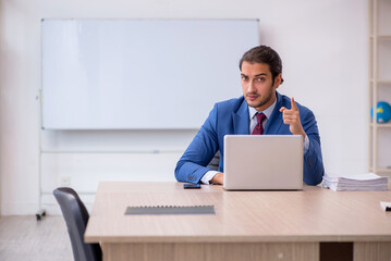 Young male employee sitting in the office in front of whiteboard